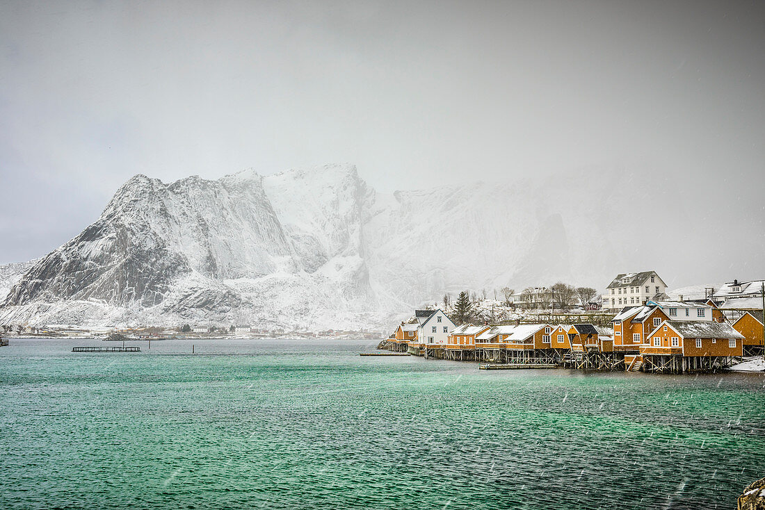 Verschneite Berge mit Blick auf die felsige Küste, Reine, Lofoten Inseln, Norwegen