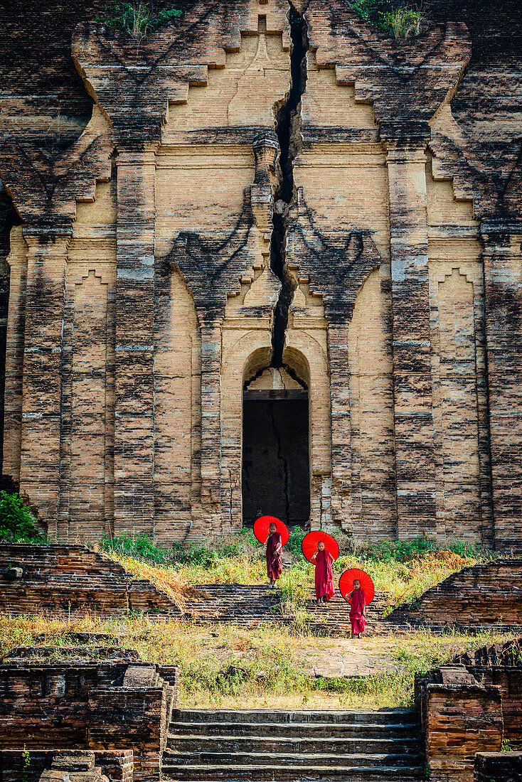 Asiatische Mönche stehen unter Sonenschirmen in der Nähe des historischen Tempels, Mingun, Mandala, Myanmar