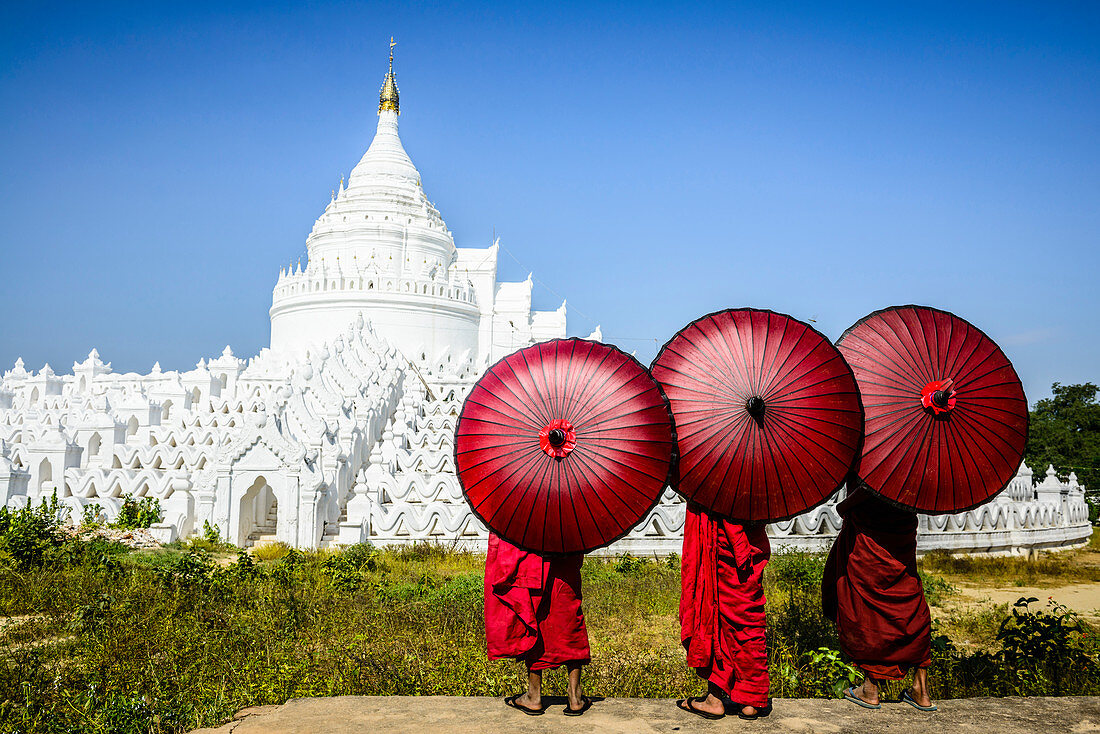 Asian monks under umbrellas viewing historic temple, Mingun, Mandala, Myanmar