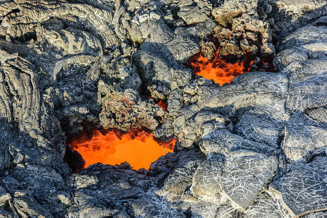 Geschmolzene Lava, die in der Nähe von getrockneter Lava glüht, Big Island, Hawaii, USA