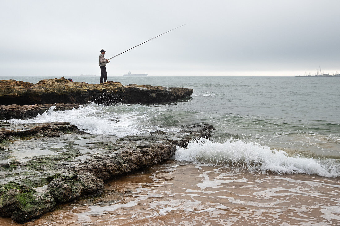Angler auf Felsen am Strand Praia do Tamariz, Cascais, Portugal