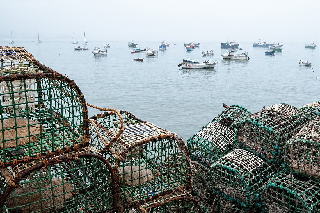 Fishing baskets and fishing boats in the fishing port of Cascais at fog, Portugal