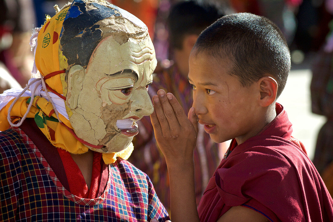 Novize flüstert mit maskiertem Tänzer bei Maskentanz, Kloster Gangteng, Phobjikha Tal, Bhutan, Himalaya, Asien