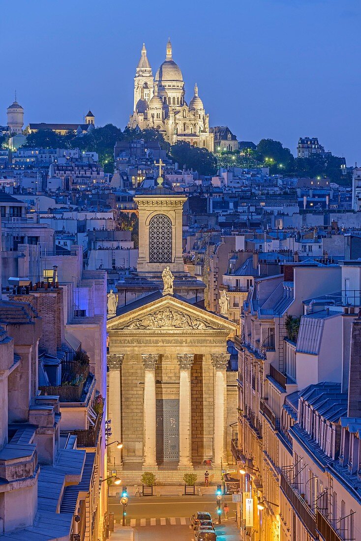 France, Paris, the Sacre Coeur basilica on the Montmartre hill and the Notre Dame de Lorette church illuminated at night