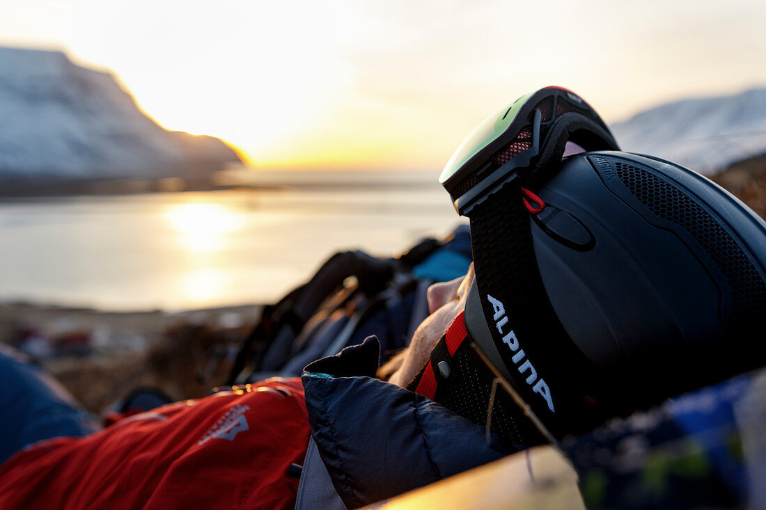 Skifahrerin liegt im Gras und genießt die letzten Sonnenstrahlen des Tages, Westfjorde, Island