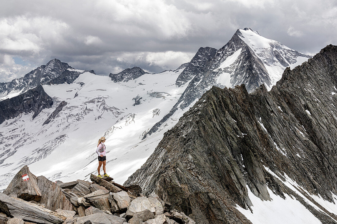 Trailrunner steht in hochalpiner Landschaft auf einem Grat, Schönbichler Horn, Schlegeis, Zillertaler Alpen, Tirol, Österreich