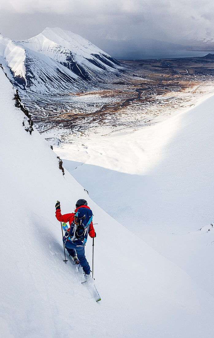 Skier on a steep slope with changing weather in the Westfjords, Iceland