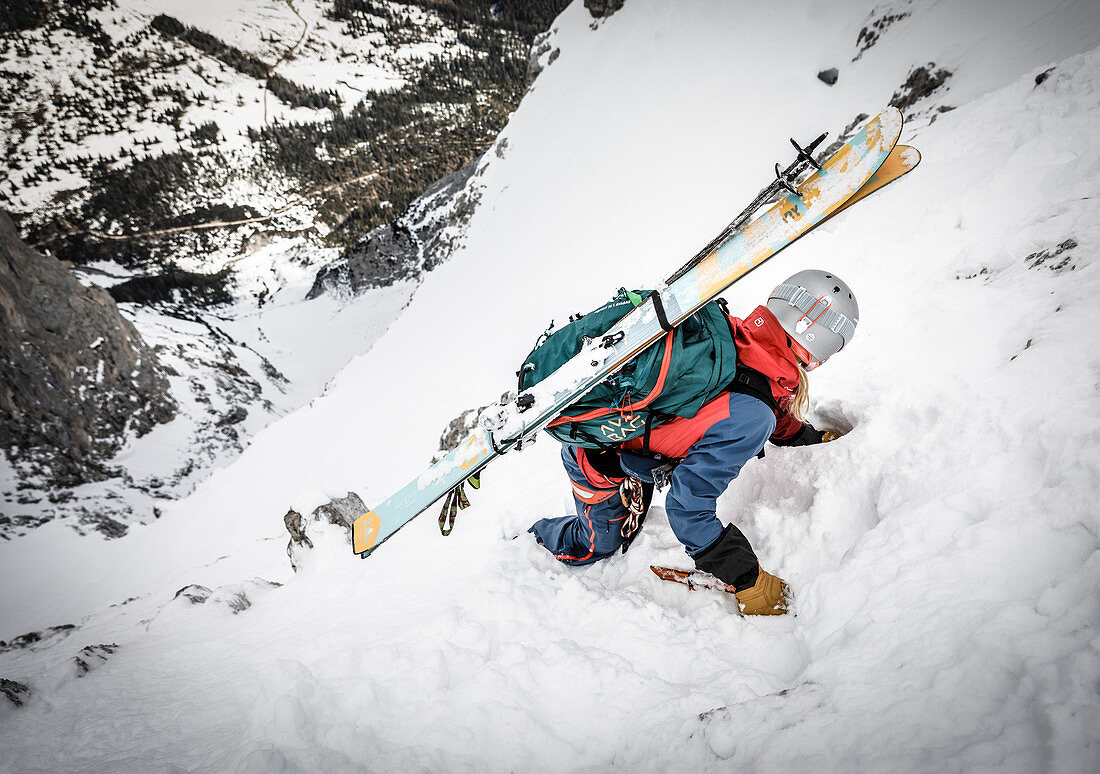 Skialpinistin beim Abstieg mit Pickel und Steigeisen im felsdurchsetzten Gelände, Mieminger Kette, Tirol, Österreich