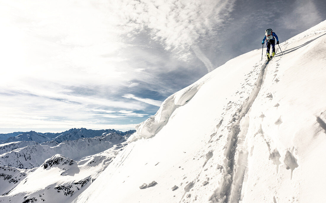 Ski tourer pulls a steep ascent trail past a change towards summit ridge, Alpbach valley, Tyrol, Austria