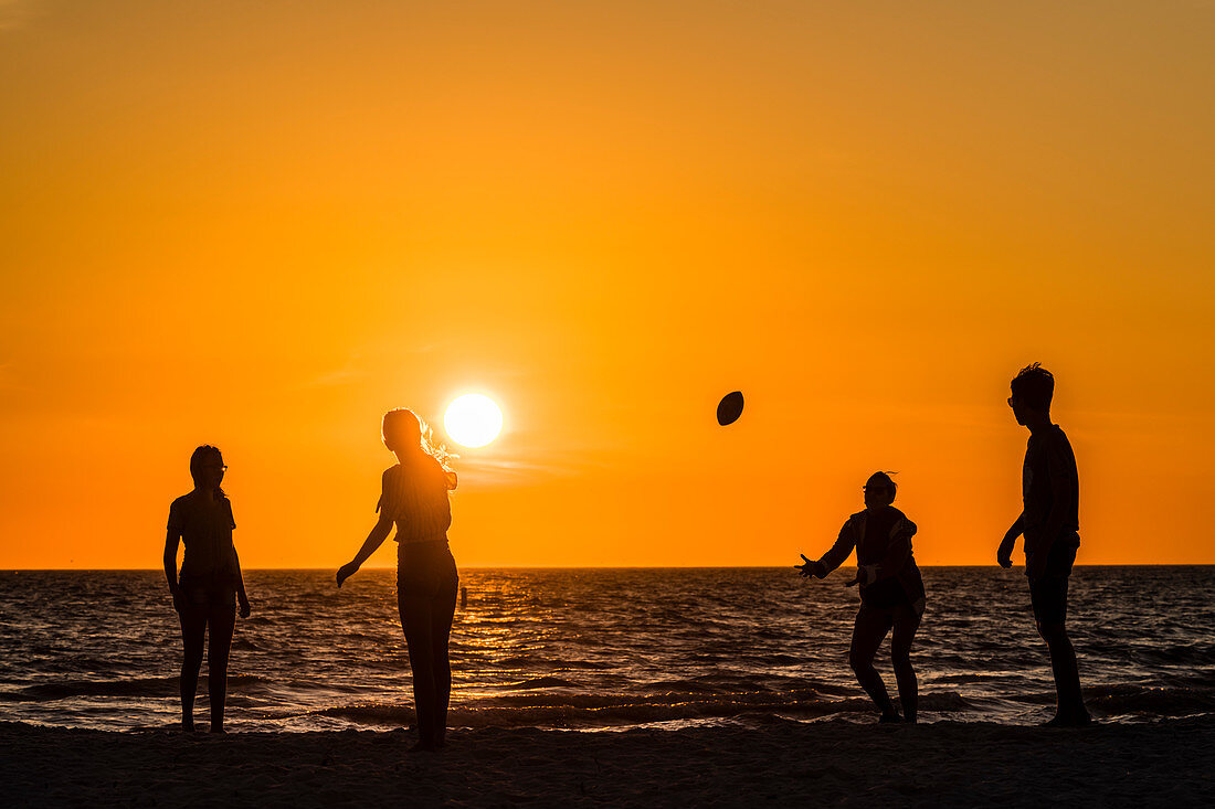 American Football am Strand vom Golf von Mexiko zum Sonnenuntergang, Fort Myers Beach, Florida, USA