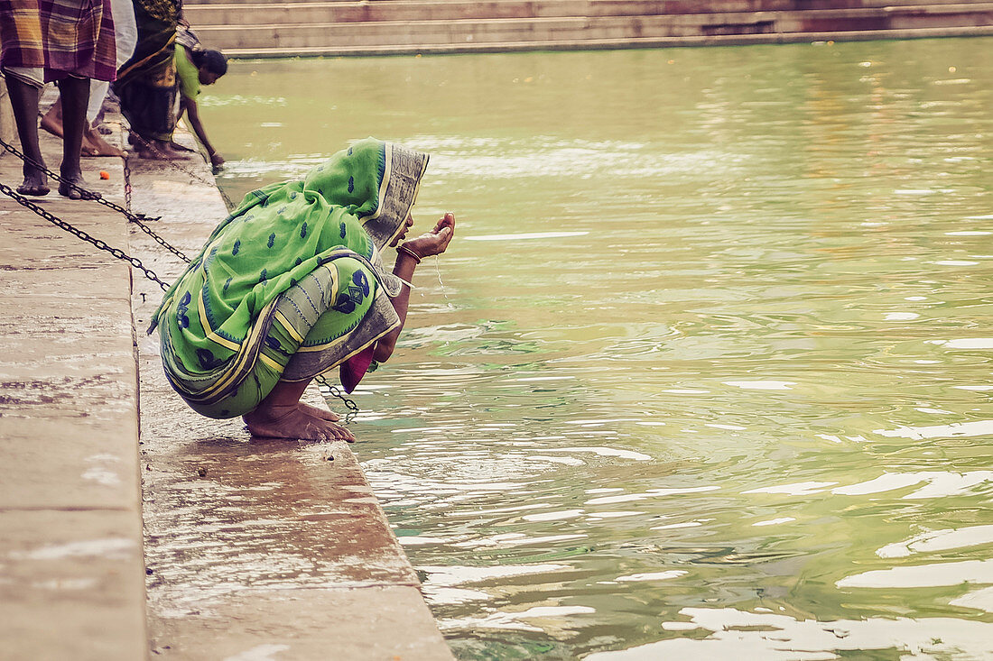 Radhakund, Vrindavan, Uttar Pradesh, Indien, Frau trinkt das heilige Wasser des Radhakunds