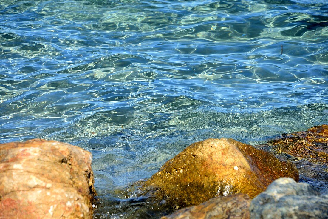 Klares Meerwasser und kleine Felsen in der Bucht von Saint-Florent, Nord- Korsika, Frankreich