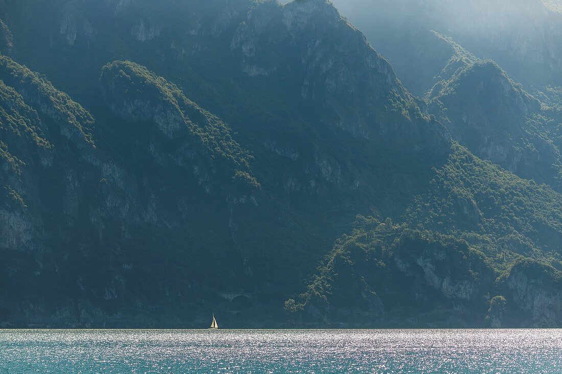 Lonely sailboat in front of the steep bank of Lake Iseo, Italy