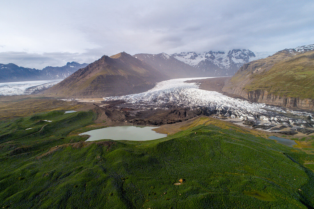 Blick auf die bergige Vulkanlandschaft mit Gletscher und See, Island