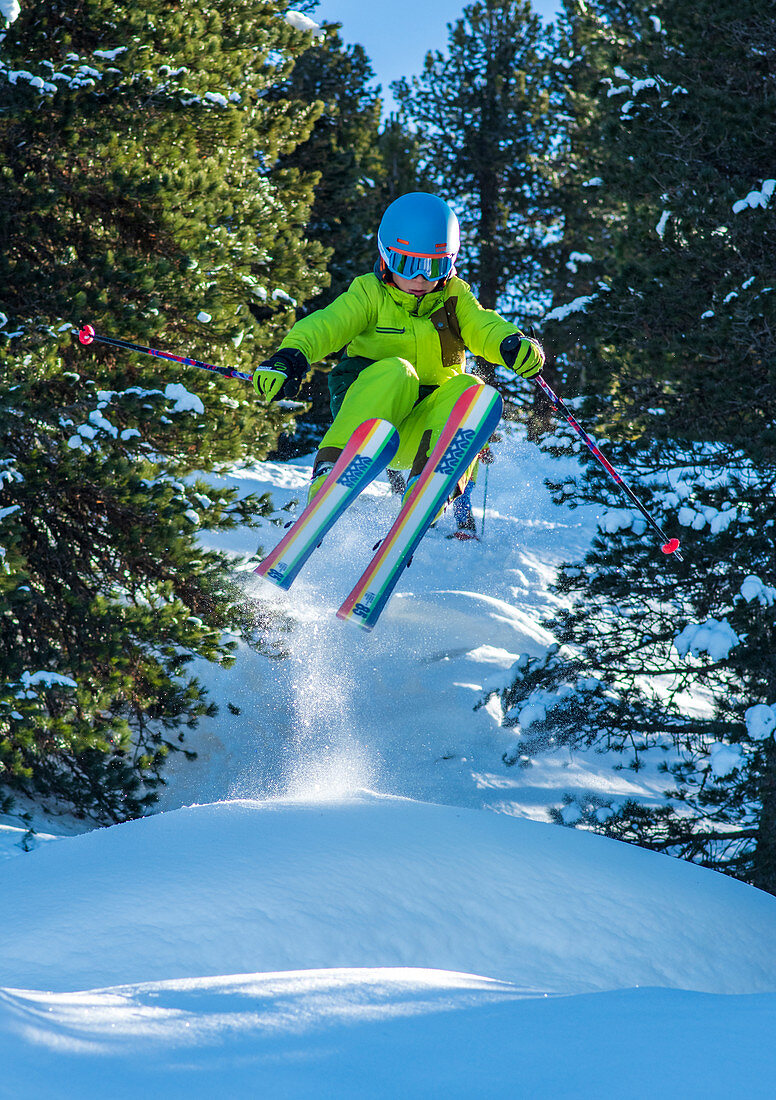 Kind springt auf Ski im Tiefschnee
