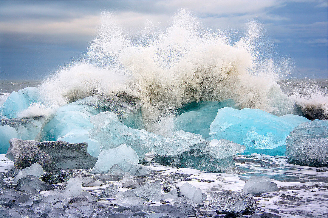 A wave breaking on the icebergs on Diamond Beach in southeast Iceland, Breidamerkursandur, Iceland, Europe