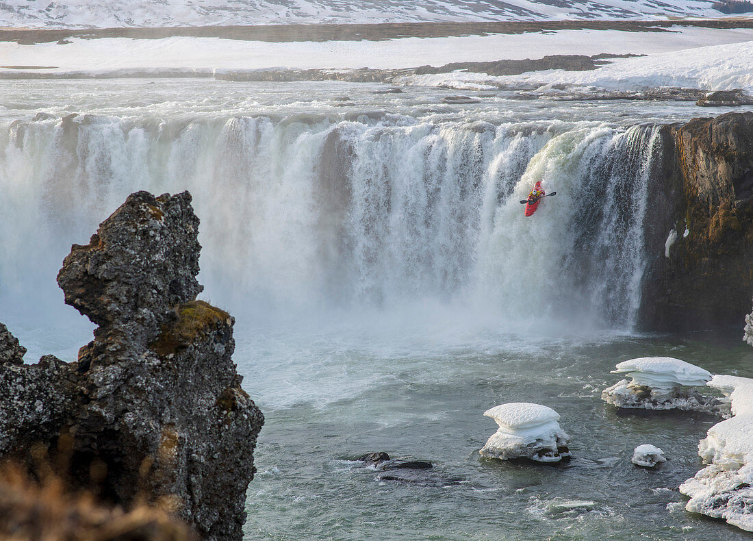 Kajakfahrer im eisigen Wasserfall Godafoss, Island im Winter