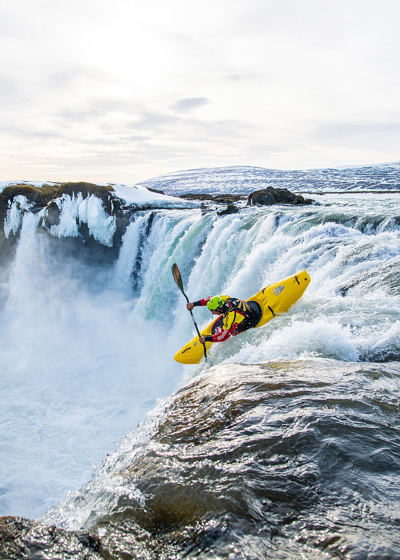 Kajakfahrer im eisigen Wasserfall Godafoss, Island im Winter