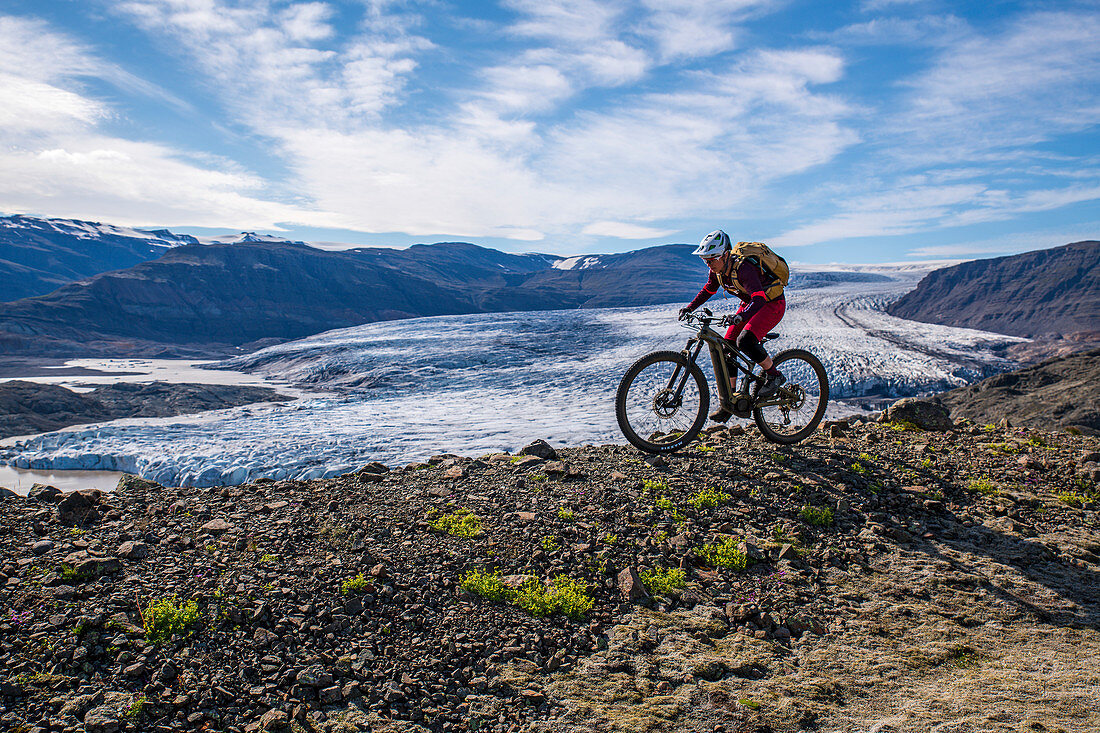 Mountainbiker fährt an einem kleinen Gletscher entlang, Island
