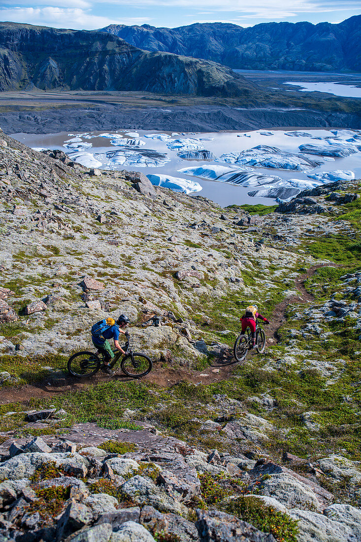 Zwei Mountainbiker fahren zu einem kleinen Gletschersee, Island