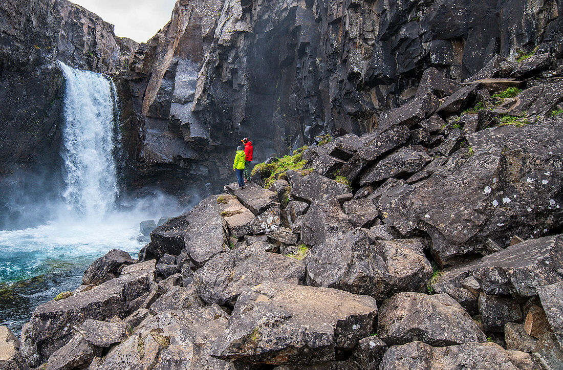 Zwei Wanderer vor einem Wasserfall in Island