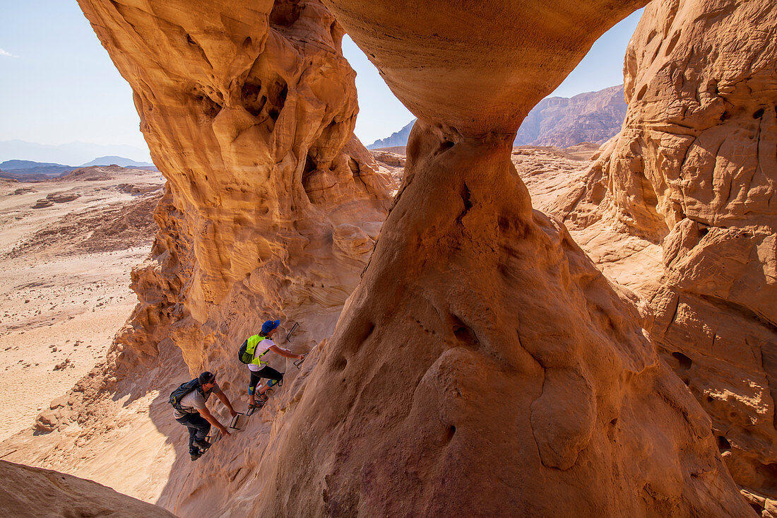 Zwei Wanderer klettern auf Felsformation in der Wüste Negev, Israel