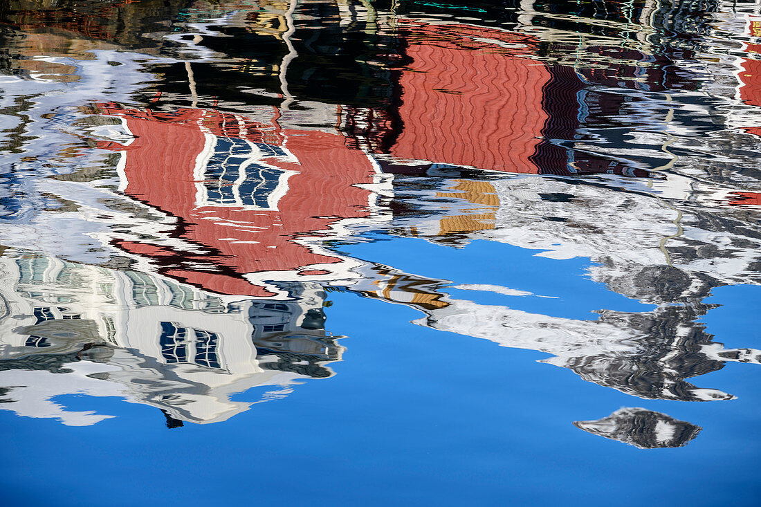 Norwegian red fishermen's houses are reflected in the sea, Klingenberg, Lofoten, Nordland, Norway