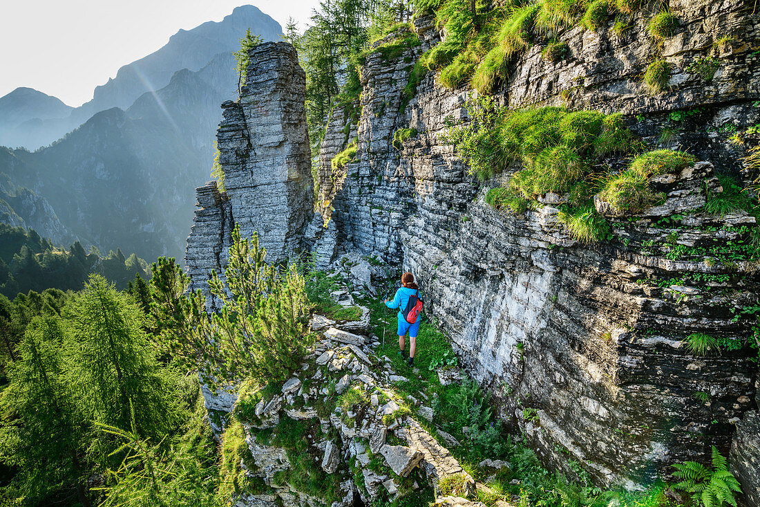 Woman hiking past banded rock wall, Schiara, Bellunesian Dolomites National Park, Dolomites, UNESCO World Heritage Dolomites, Veneto, Italy