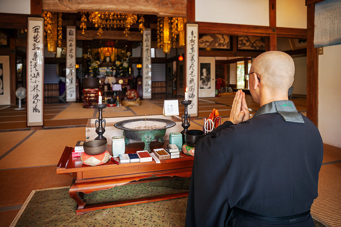 Buddhistischer Priester kniet und betet im buddhistischen Tempel