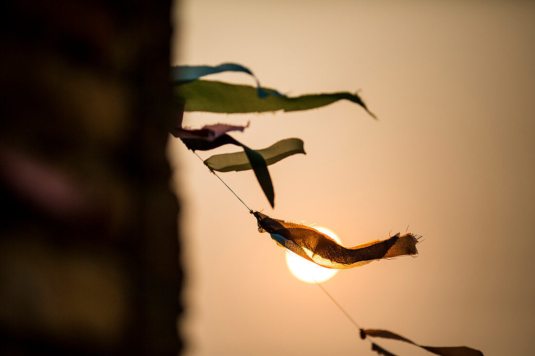 Low angle close up of prayer flags fluttering in the wind at sunset.