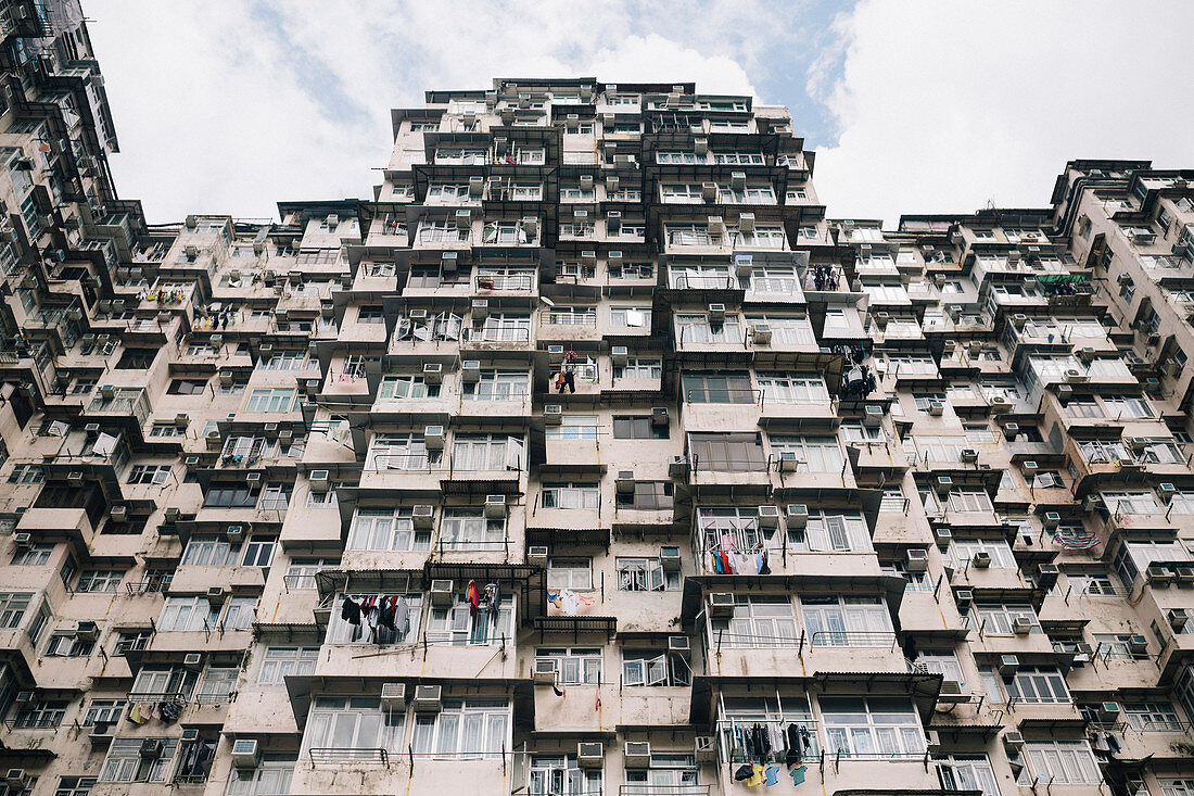 Low angle view of facade of towering residential complex with windows and balconies.