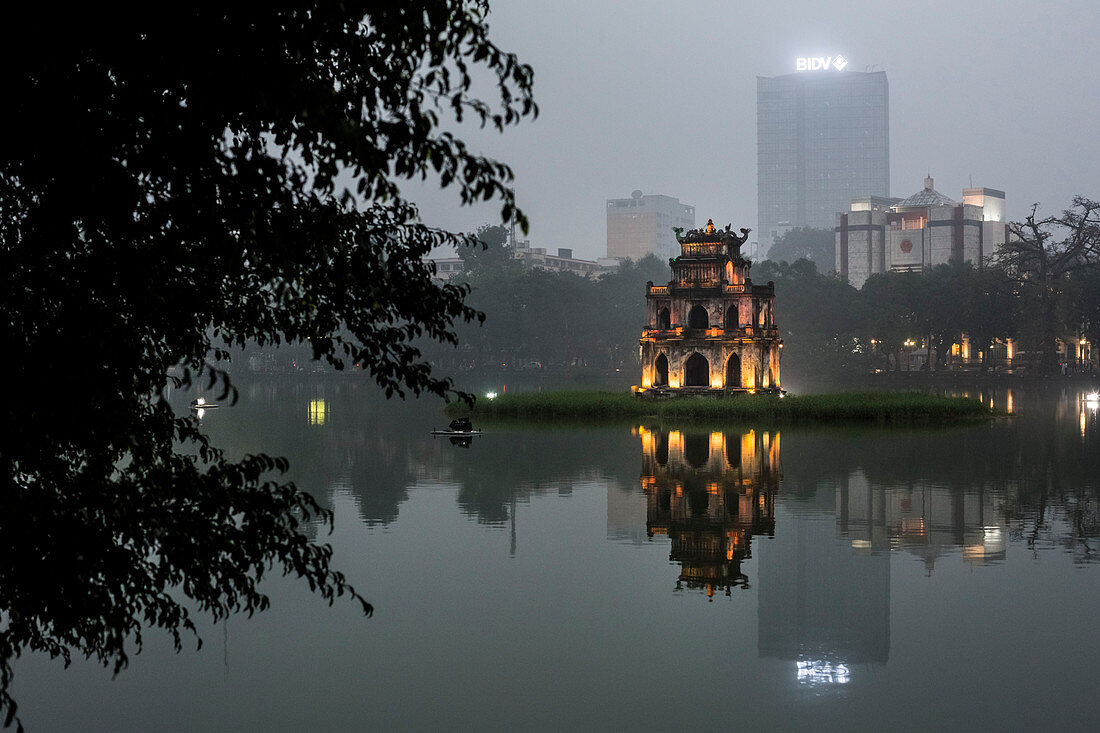 Beleuchteter Tempel spiegelt sich in einem See bei Abenddämmerung, Wolkenkratzer in der Ferne