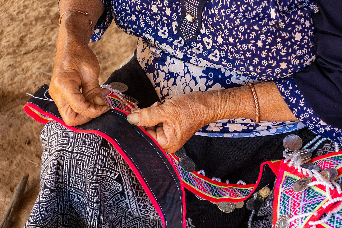 Woman seated stitching, making tradtional garments, Vang Vieng, Laos