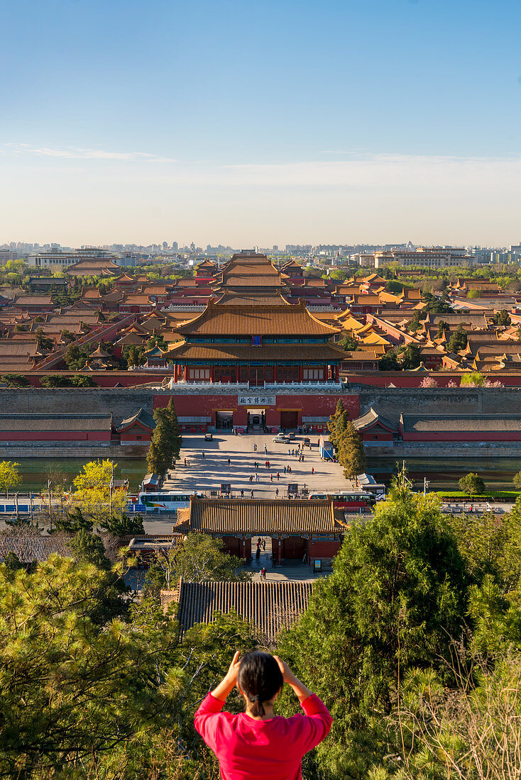 Young woman taking photograph of view over Forbidden City in Beijing, China