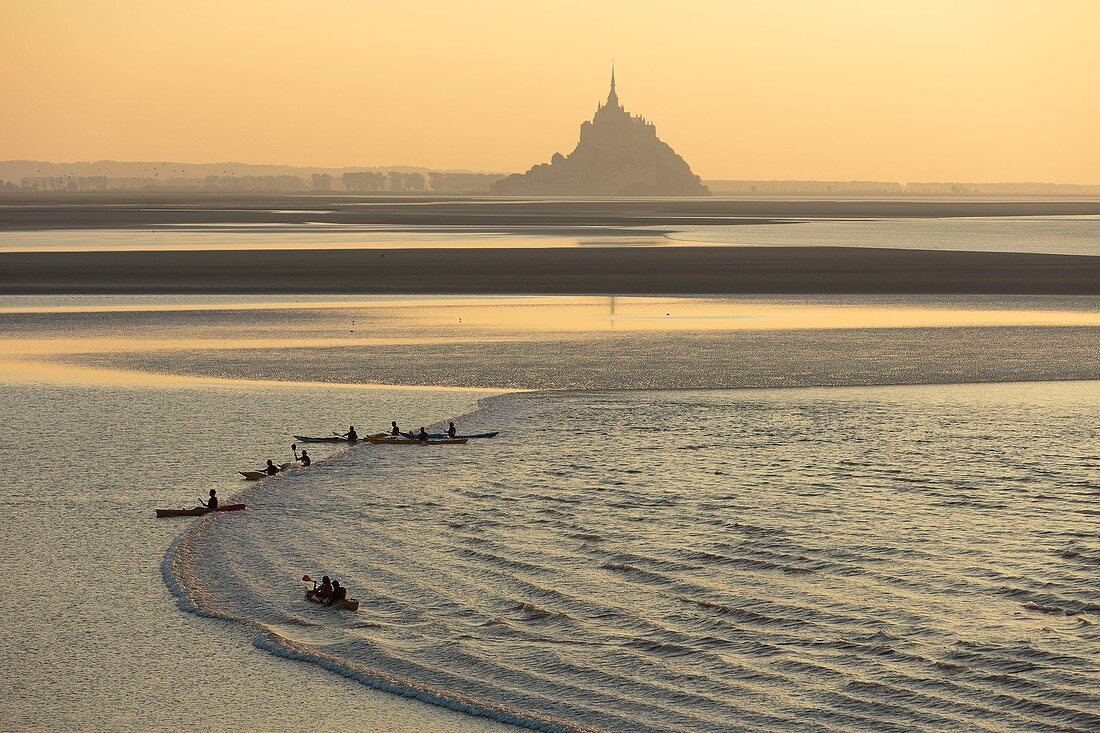 France, Manche, Mont Saint Michel bay, listed as World Heritage by UNESCO, a kayakists riding the Mascaret wave during fall high tides and Tombelaine islet in the background