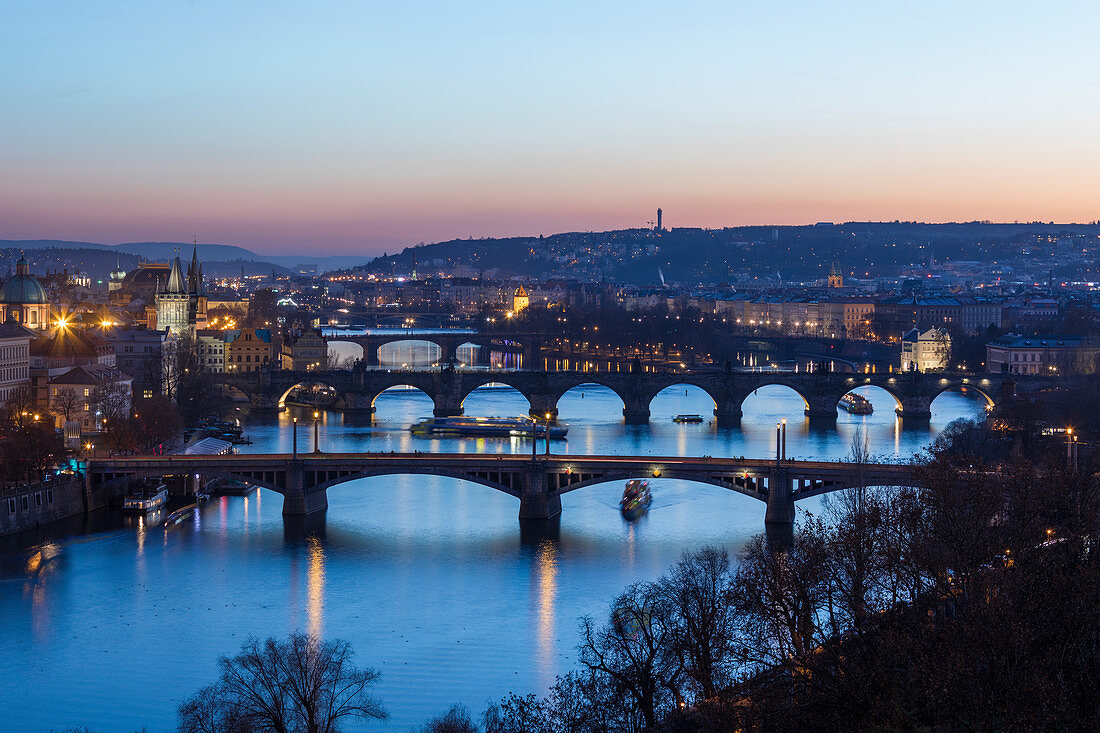 Dusk lights up the historical bridges and buildings reflected on Vltava River, Prague, Czech Republic, Europe