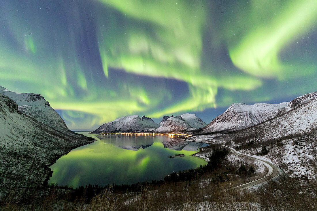 Northern lights (aurora borealis) and stars light up the snowy peaks reflected in the cold sea, Bergsbotn, Senja, Troms, Norway, Scandinavia, Europe