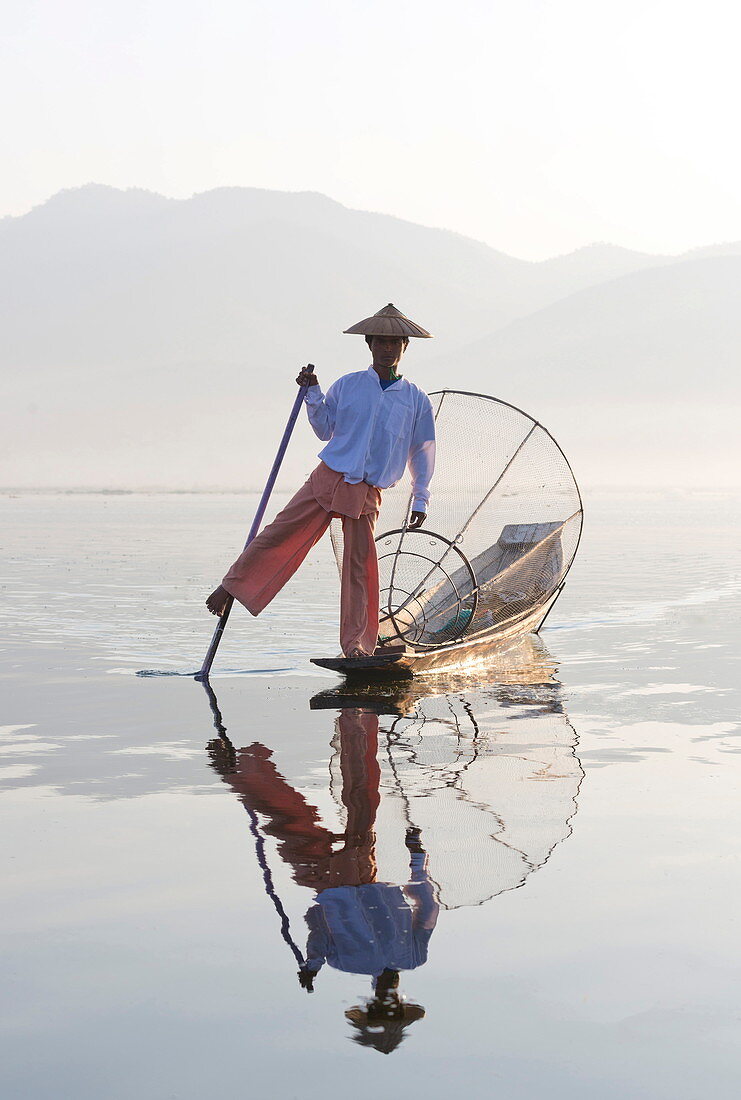 Intha 'Einbeinruderer' Fischer auf dem Inle-See, die traditionelle Holzboote mit ihrem Bein rudern und mit Netzen über konische Bambusrahmen fischen, Inle-See, Myanmar (Burma), Südostasien