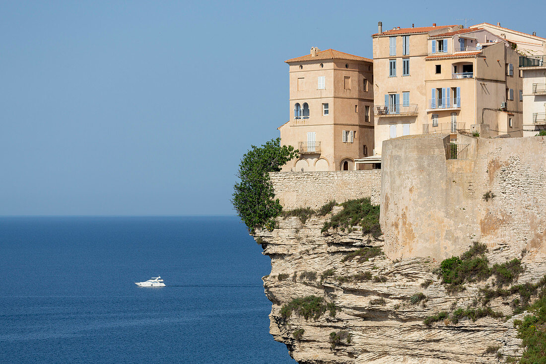 The Citadel and old town of Bonifacio perched on rugged cliffs with boat in the Mediterranean sea, Bonifacio, Corsica, France, Mediterranean, Europe