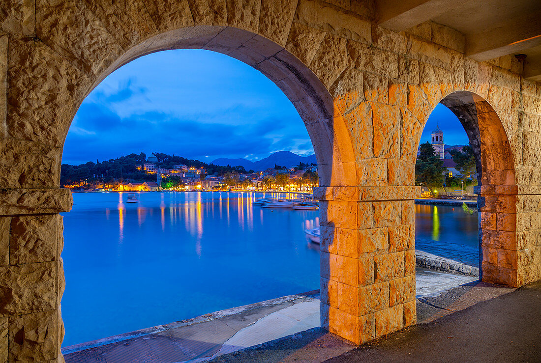 Blick auf die Stadt und die St. Nikolaus Kirche durch Bögen in der Dämmerung, Cavtat an der Adria, Cavtat, Riviera Dubrovnik, Kroatien, Europa