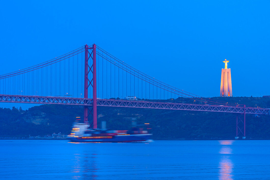 Containerschiff unter der Brücke vom 25. April und Almada Cristo Rei Statue bei Sonnenuntergang, Stadtteil Belem, Lissabon, Portugal, Europa