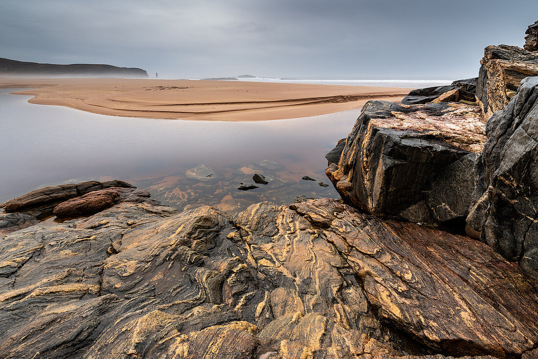 Felsformationen in Sandwood Bay, mit Am Buachaille Brandungspfeiler in weiter Entfernung, Sutherland, Schottland, Großbritannien, Europa