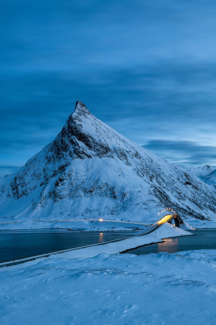 Fredvang-Brücke gesetzt gegen pyramidenförmigen Berg bei Nacht mit Lichtspuren, Lofoten, Arktis, Norwegen, Europa