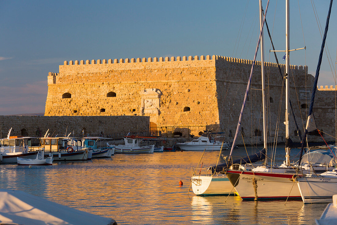 View across the Venetian Harbour, sunset, the Koules Fortress reflected in water, Iraklio (Heraklion), Crete, Greek Islands, Greece, Europe