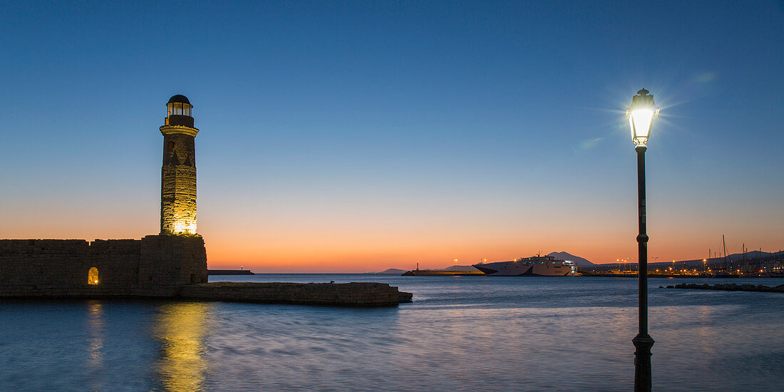 Panoramic view across entrance to the Venetian Harbour, dawn, lighthouse prominent, Rethymno (Rethymnon), Crete, Greek Islands, Greece, Europe