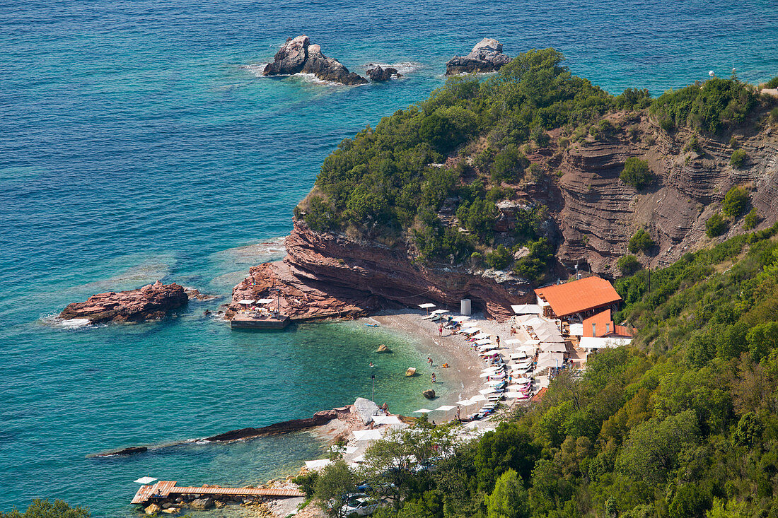 Blick von der Klippe über geschützte Bucht von klarem türkisfarbenem Wasser, Sveti Stefan, Budva, Montenegro, Europa