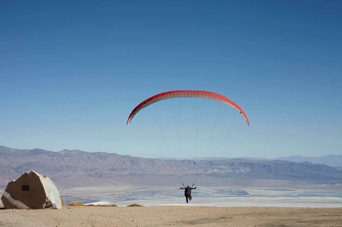Paraglider takes off in a blue sky in front of the White Mountains. Walts Point at Lone Pine, California, USA.