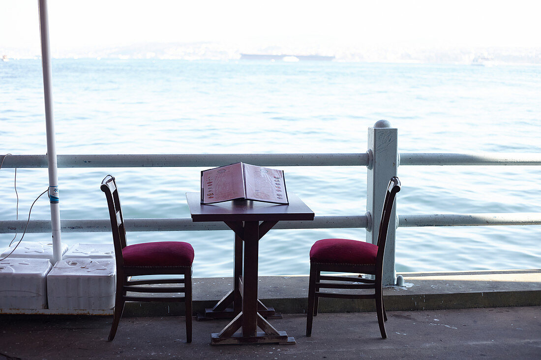 Tisch mit zwei Stühlen auf der Restaurantebene der Galata Brücke in Istanbul, Türkei