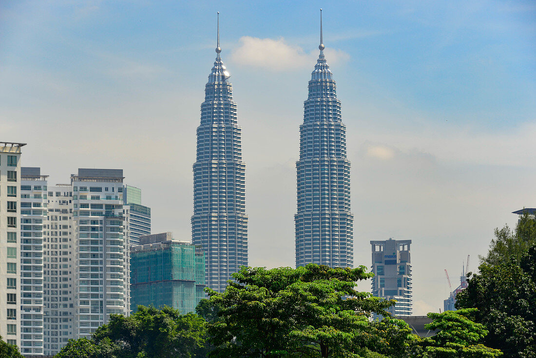 Die Petronas Towers mit Skyscrapern und Bäumen in Kuala Lumpur, Malaysia