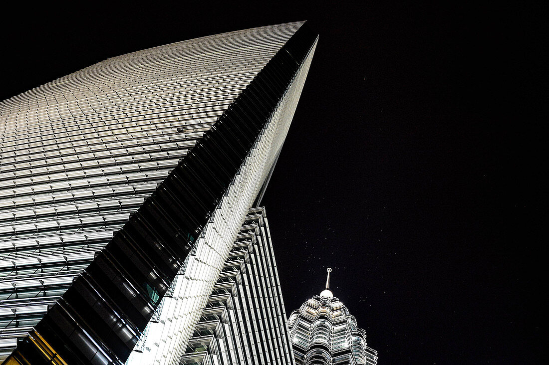 Nocturnal view of an illuminated skyscraper and the Petronas Tower from an unusual perspective, Kuala Lumpur, Malaysia